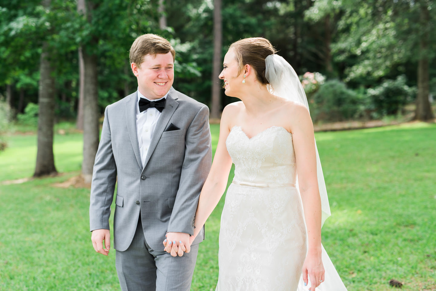 Southern bride and groom smiling at each other while walking during Mississippi outdoor wedding