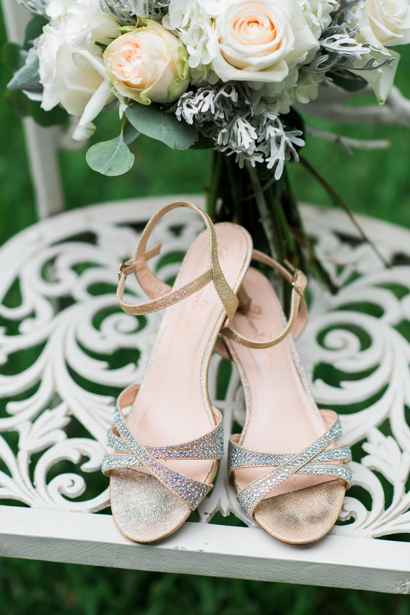 Bride's shoes and bouquet on white wrought iron chair photographed by Ashley Schurch Photography