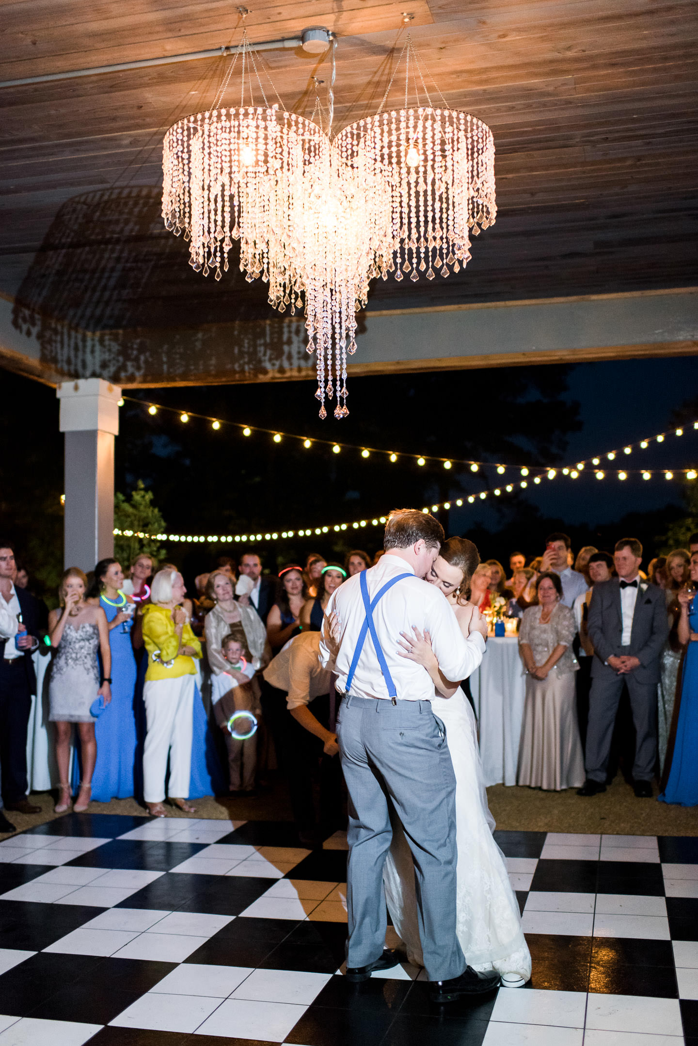 Mississippi bride and groom's first dance on black and white dance floor under chandelier during their southern outdoor wedding reception