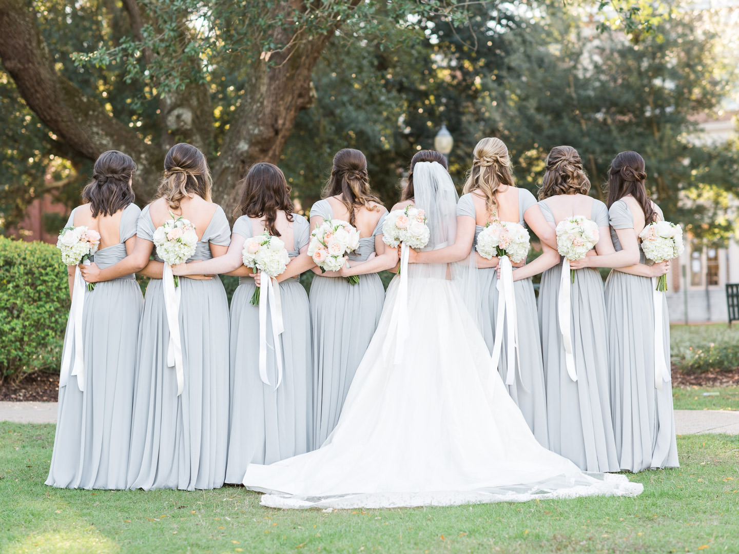 Bridesmaids with grey long bridesmaids dresses and neutral and coral bouquets