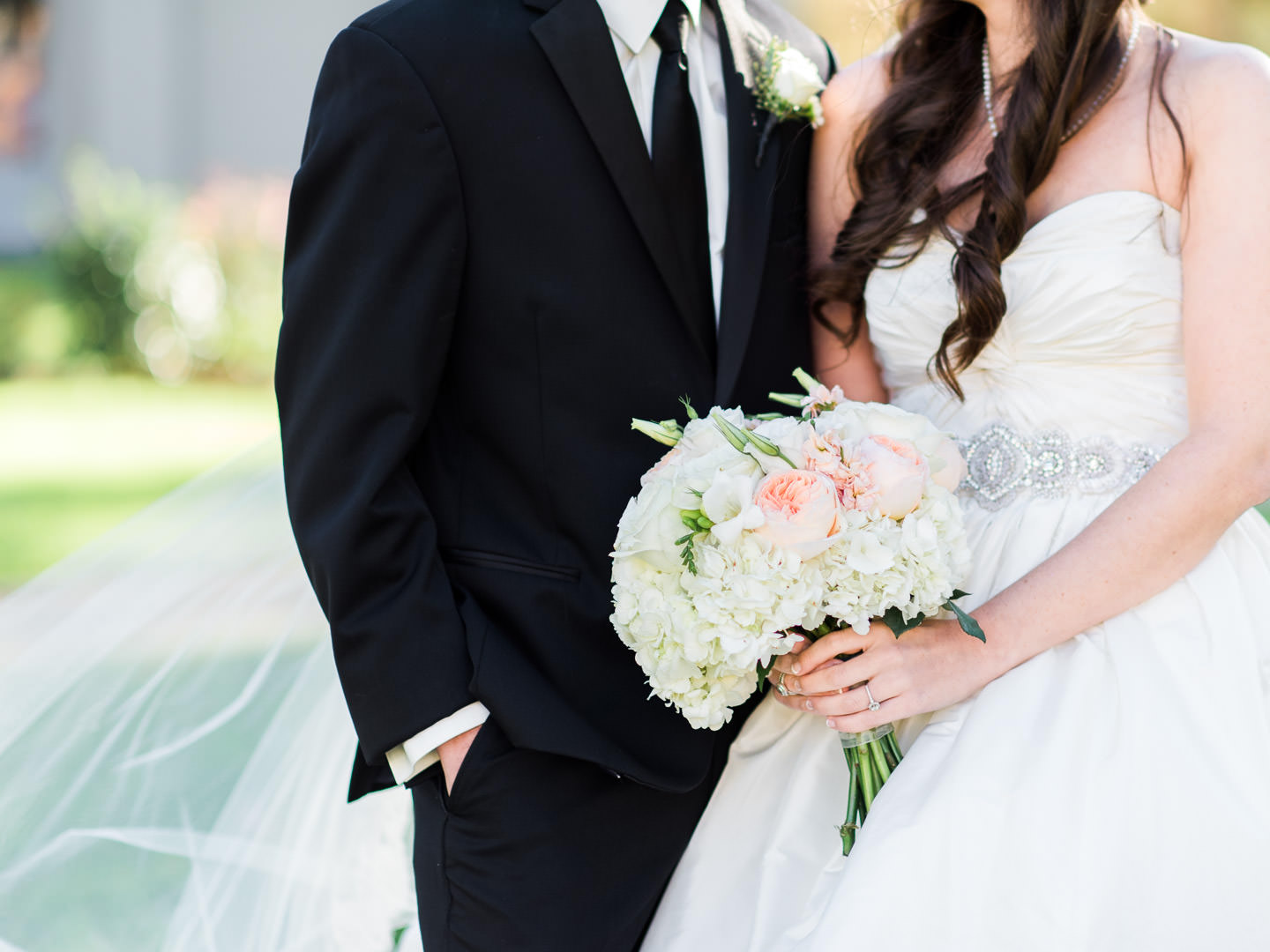 Groom with Black suit and tie and Bride with belt, coral juliette roses and hydrangeas