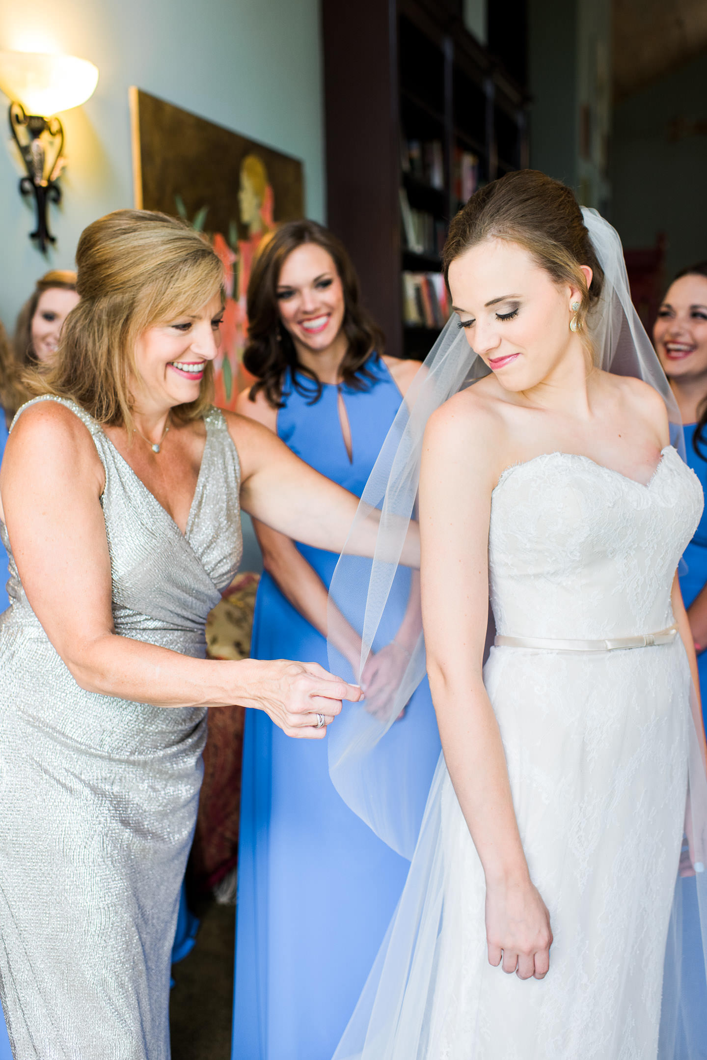 Mother of the bride fixes bride's veil with bridesmaids looking on while getting ready for outdoor Mississippi wedding