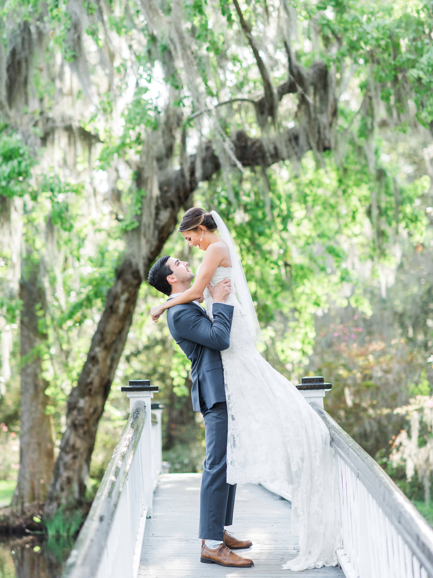 Groom lifting and twirling bride on Magnolia Plantation white bridge